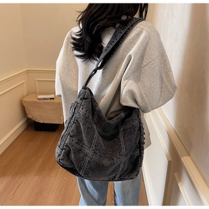 Detail of a large black denim hobo bag with white contrast stitching for women