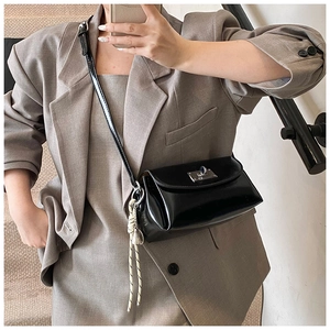 Détail du sac à bandoulière en cuir verni noir avec boucle argentée et pendentif