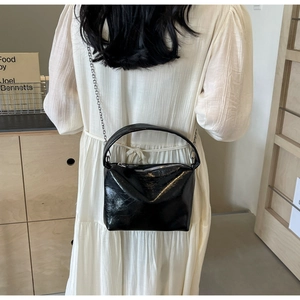 Detail of glossy black patent leather bag featuring unique crinkled texture and silver chain