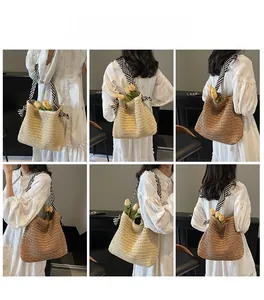 Detail of hollow-out straw woven tote bag with black and white striped shoulder strap