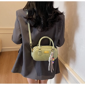 Détail du sac à main vert clair avec plaque dorée et pendentif à perles colorées