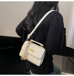 Detail view of cream leather crossbody bag with striped scarf and gold hardware accents