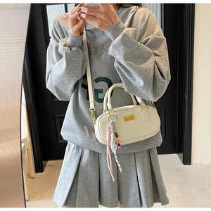 Sac bowling blanc ovale avec détails dorés et breloques en perles sur la bandoulière