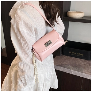 Détail du sac à main en cuir rose avec fermoir argenté et breloque en corde rayée