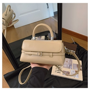 Detail of elegant beige crossbody handbag featuring silver metal rings and smooth leather strap
