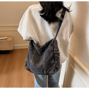 Detailed close-up of dark grey denim tote bag with white stitching and frayed edges