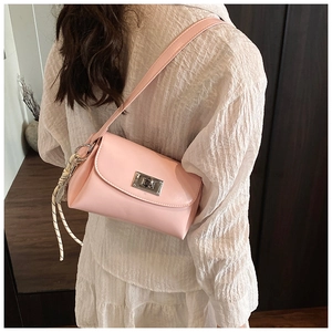 Détail du sac bandoulière rose avec fermoir argenté et pendentif tissé décoratif