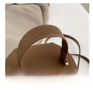 Gros plan détaillé de la poignée du sac seau en cuir marron avec boucle dorée