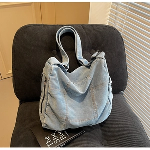 Detail of light blue denim patchwork tote bag showing side zipper on corduroy seat