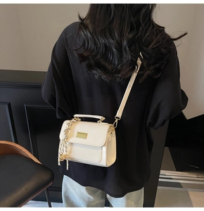 Close-up of off-white crossbody bag featuring a golden buckle and decorative silk scarf