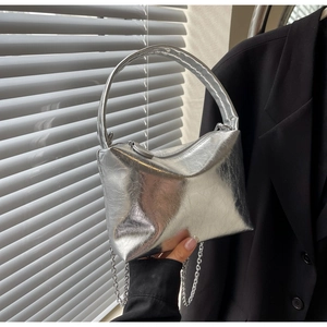 Close-up of a silver metallic pleated pillow bag with chain strap and hand grip details