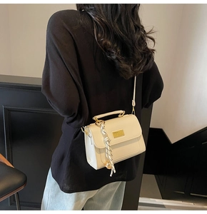 Close-up of cream square crossbody bag with gold plaque and striped silk scarf detail