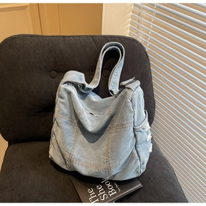 Detailed view of light blue denim tote bag featuring side pockets with frayed edges