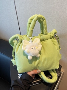 Minimalist puffy light green bucket bag with plush monster charm and top handle strap