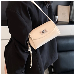 Détail du sac à bandoulière crème avec fermoir rotatif argenté et breloque tissée