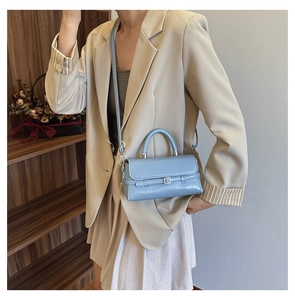 Close-up of light blue leather crossbody bag with buckle detail and shoulder strap