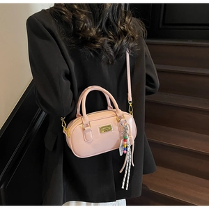 Détail d'un sac bowling en cuir rose avec ferrures dorées et breloque perlée tendance
