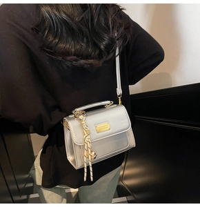 Detail of silver metallic crossbody bag with gold buckle and stylish knot charm