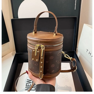 Vue détaillée du sac seau en cuir marron avec motifs de chien dans son coffret