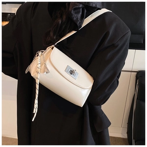 Détail d'un sac à bandoulière en cuir beige avec fermoir argenté et pendentif tissé chic