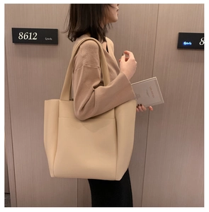Detailweergave van een grote beige draagtas gedragen door een model voor houten wand