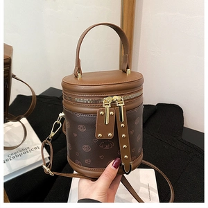 Détail d'un sac seau cylindrique marron avec graffitis et ferrures dorées