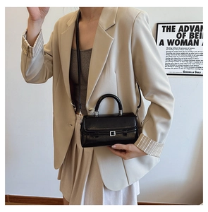 Model wearing a black patent leather square bag with silver buckle and top handle