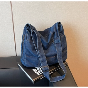 Detail of vintage blue washed denim tote bag with side metal zipper and stitching