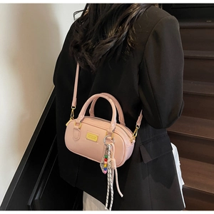 Sac Boston en cuir verni rose avec plaque dorée et breloque à pompons colorés
