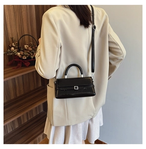 Rear view of a black patent leather mini square bag worn with a white blazer