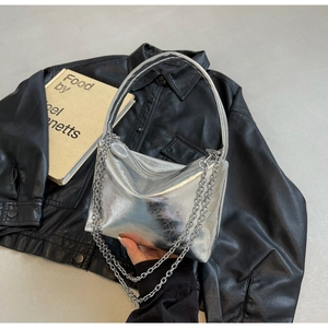 Detail of silver metallic wrinkled leather pillow bag with chain strap on jacket
