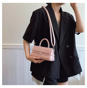 Mini pink crossbody square bag with metal buckle detail shown on black blazer suit