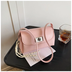 Détail du sac bandoulière rose clair avec fermoir rotatif argenté et pompon tissé