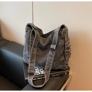 Detail of washed denim tote bag showing contrast stitching and distressed fringe texture