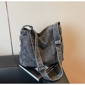 Detail of dark gray washed denim bag featuring contrast stitching and adjustable strap