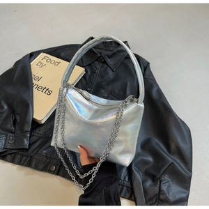Close-up of holographic silver pillow bag with metallic chain on leather jacket