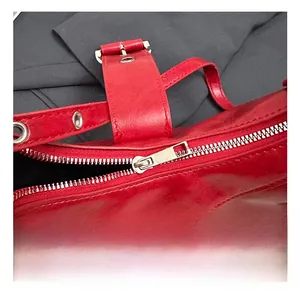 Detail of red glossy leather shoulder bag with silver hardware and adjustable wide strap