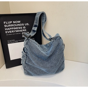 Detail of adjustable strap and frayed side pocket on vintage large denim tote bag