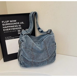 Close-up of vintage blue denim tote bag with brown contrast stitching and side zipper