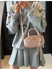 Sac Boston rose en cuir avec fermeture dorée et breloque colorée au style urbain décontracté