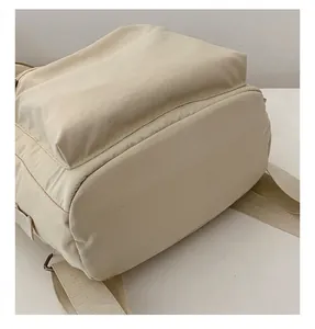 Detalle de la textura de nailon beige y costuras reforzadas en la base de la mochila