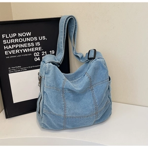 Detailed patchwork texture and side zipper on a light blue denim tote bag with strap