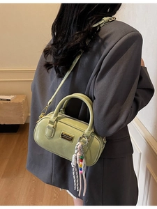 Sac bowling vert sauge en cuir avec plaque dorée et bandoulière porté par mannequin