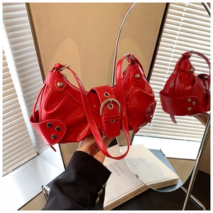 Macro shot of glossy red shoulder bag with metal studs and large buckle details