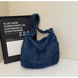 Detail of blue denim crossbody bag with contrast stitching and adjustable wide strap