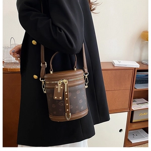 Détail du sac cylindre marron vintage avec motifs chien et accessoires dorés