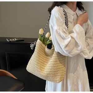 Detail of hand-woven straw tote bag with black and white patterned fabric shoulder strap