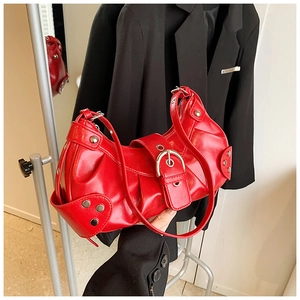 Detail view of a glossy red moon-shaped shoulder bag with silver buckle and metal studs
