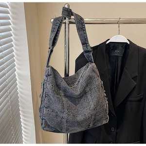 Detail of grey denim tote bag featuring white quilted stitching and wide shoulder strap