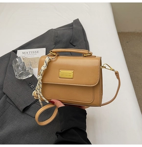 Detail of camel square handbag with gold metal plaque and contrast knotted handle